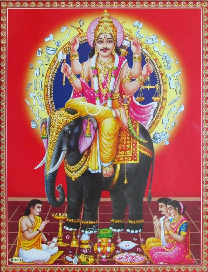 Lord Vishwakarma riding an elephant against a red background with devotees performing puja below