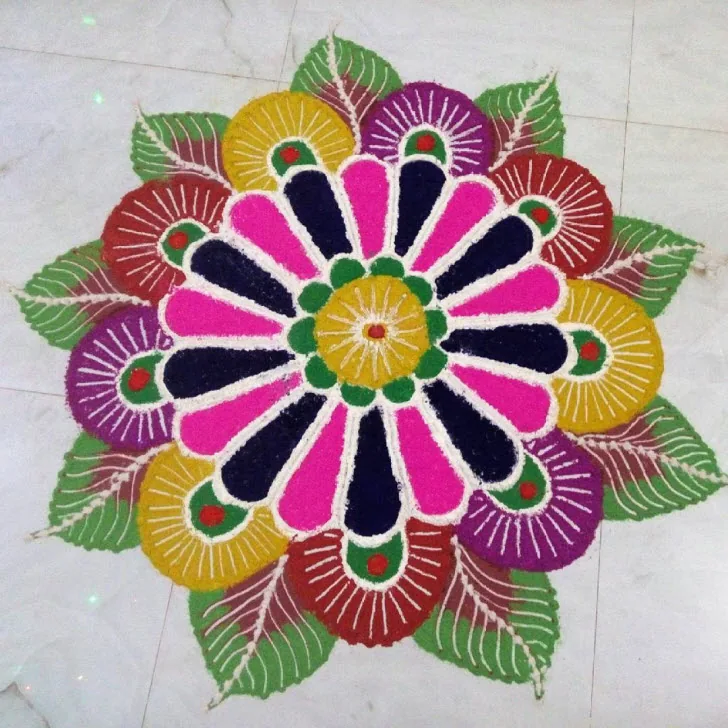 Round flower rangoli with pink, purple, yellow and dark blue petals and green leaves on a white floor